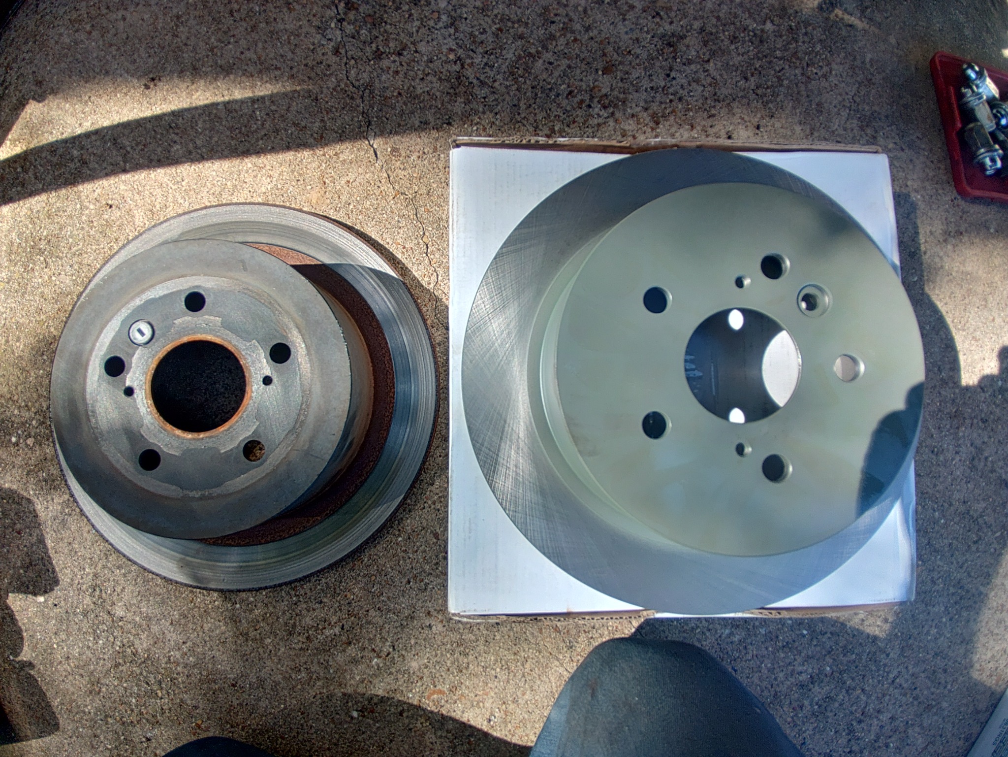 A worn brake rotor beside a replacement rotor